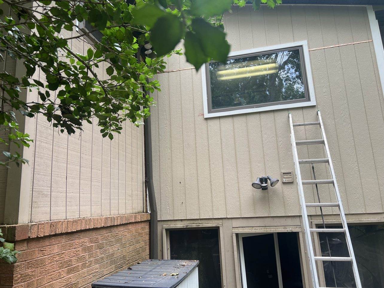 House siding corner with downspout and brick base