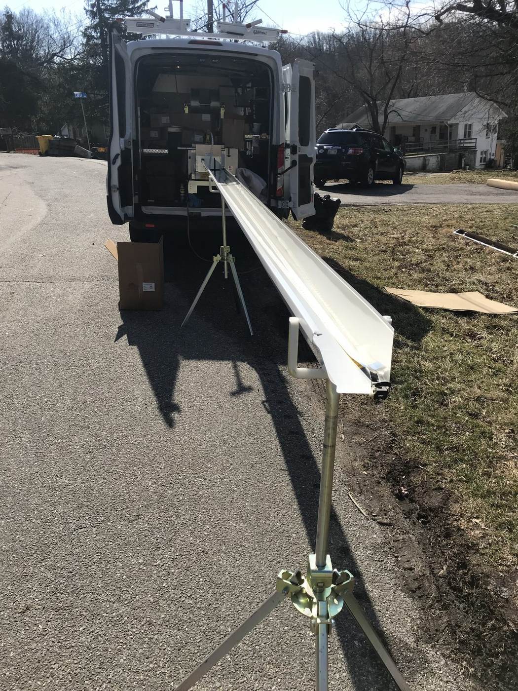 A seamless gutter machine on the truck extruding one continuous run of aluminum gutter — no joints along the whole length.